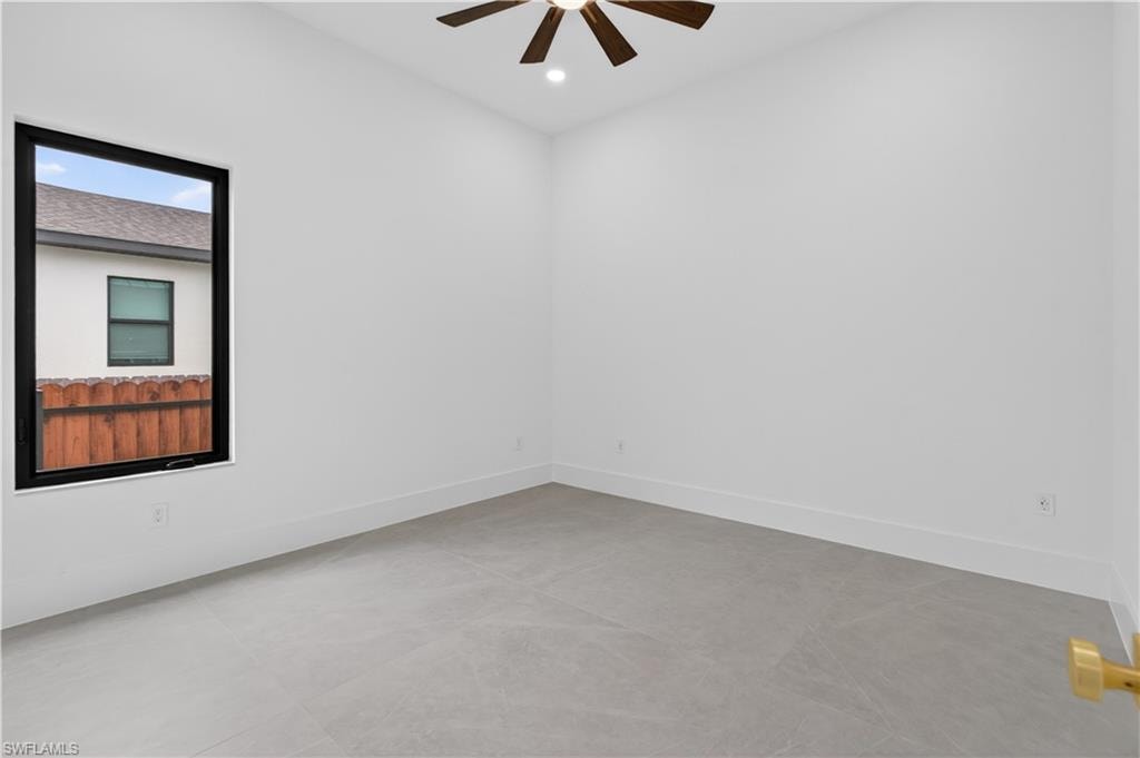 Bright interior space featuring a multi-pane window with black framing, wood-finish ceiling fan, recessed lighting, and light grey tile flooring