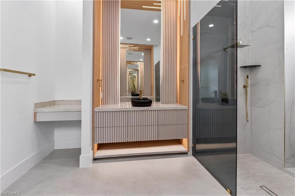 Modern bathroom featuring a fluted vanity with a vessel sink, integrated lighting, and a large mirror
