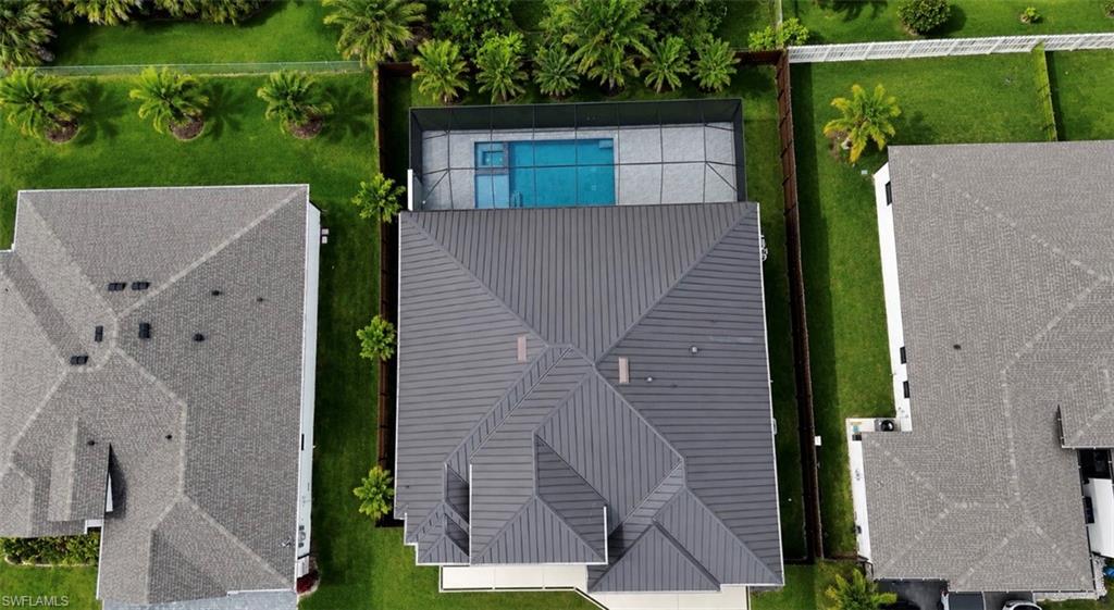 Modern residential property featuring a gray metal roof, private swimming pool, and screened enclosure