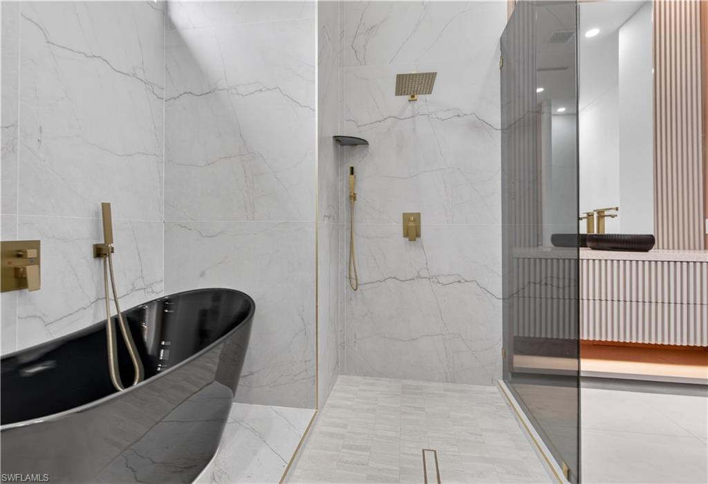 Freestanding black soaking tub with wall-mounted brass fixtures