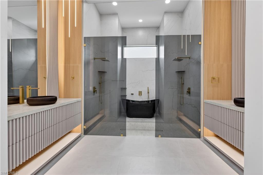 Contemporary bathroom featuring dual floating vanities with reeded paneling and integrated lighting