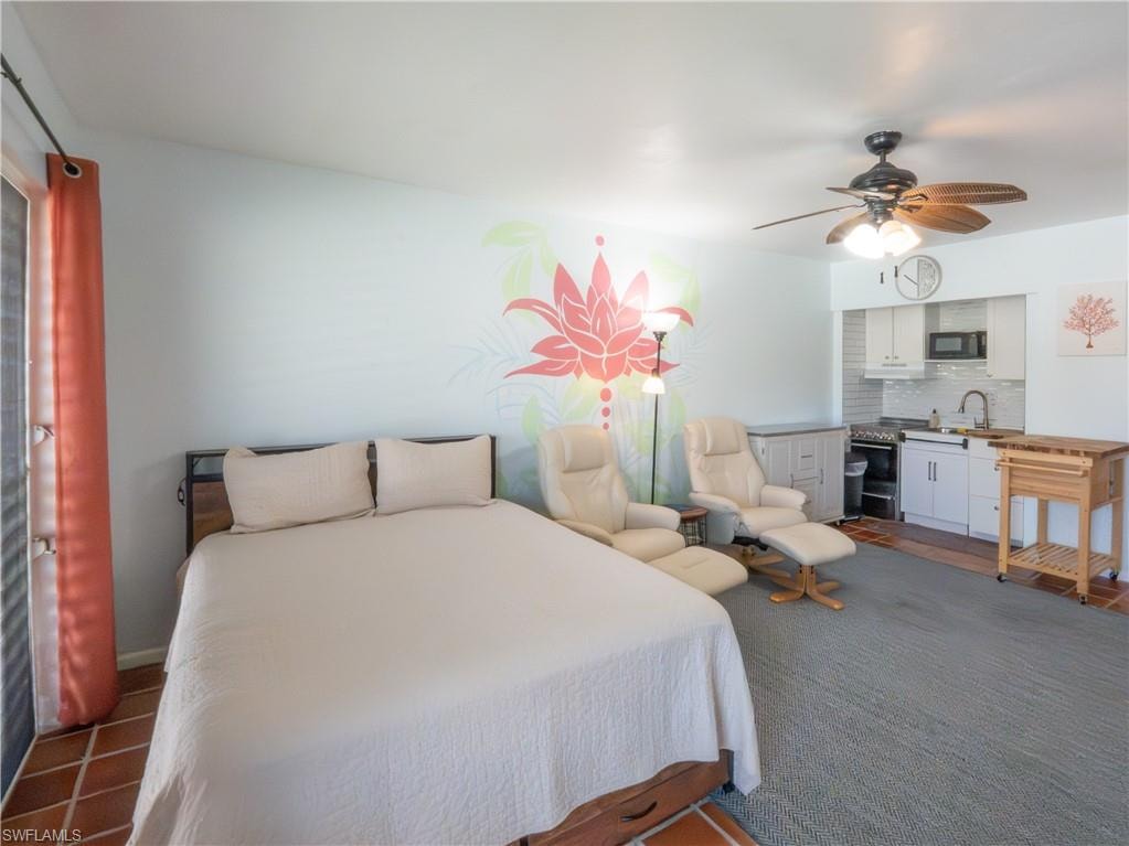 Studio living area featuring a compact kitchen with white cabinetry and a subway tile backsplash