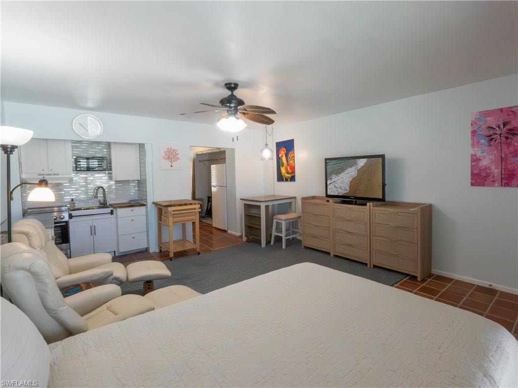 Compact living area featuring a built-in kitchenette with white cabinetry and a tiled backsplash