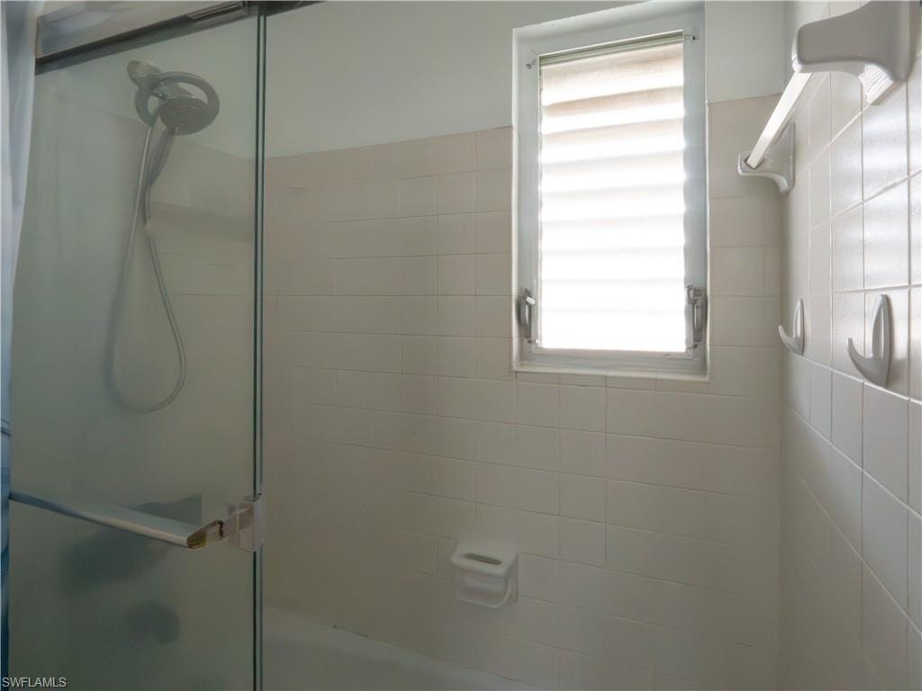 Shower enclosure with a clear glass panel and an integrated handheld showerhead