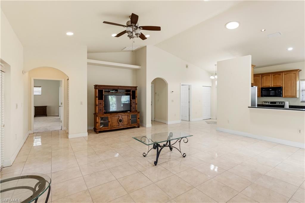 Open-concept living space featuring high vaulted ceilings, recessed lighting, and large format tile flooring