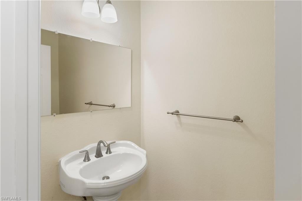 Pedestal sink with a two-handle faucet, illuminated by an overhead light fixture