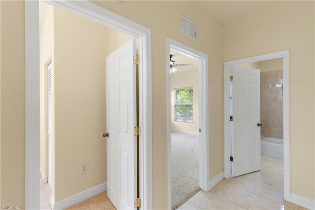 Hallway featuring neutral wall tones, white trim, and a mix of carpet and tile flooring, with access to multiple rooms