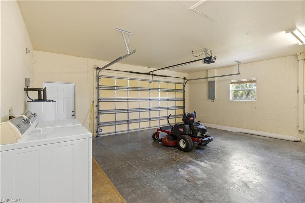 Spacious garage featuring a concrete floor, overhead garage door, and a utility area with a washer and dryer