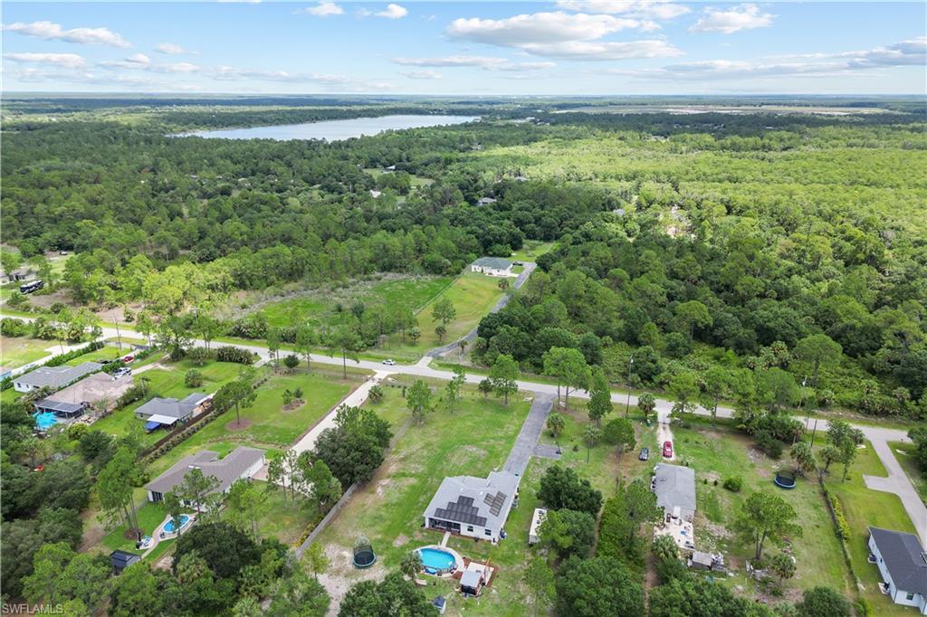 Expansive aerial view showcasing a large body of water, extensive wooded areas, and a residential community