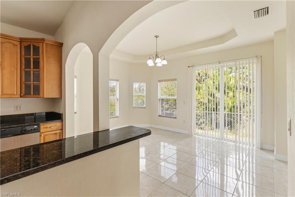 Open-concept kitchen and dining area featuring a breakfast bar with a dark stone countertop, oak cabinetry, and stainless steel dishwasher