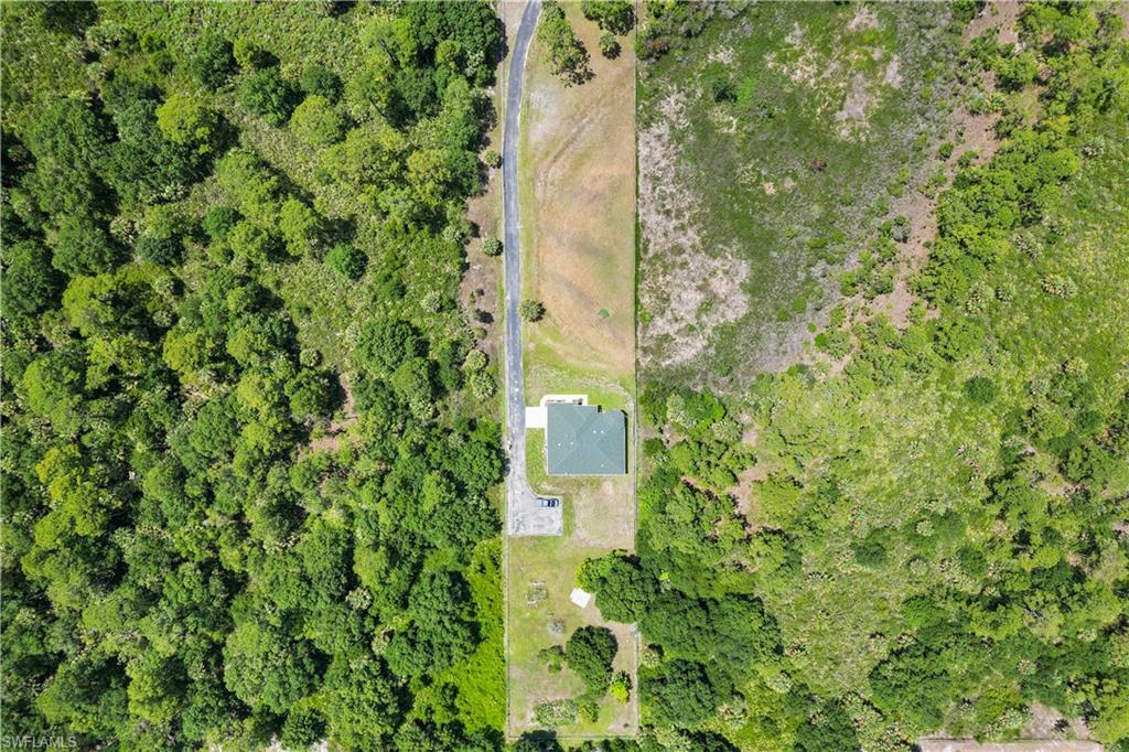 Aerial depiction of a single-story residence with a dark green roof, positioned on a cleared lot