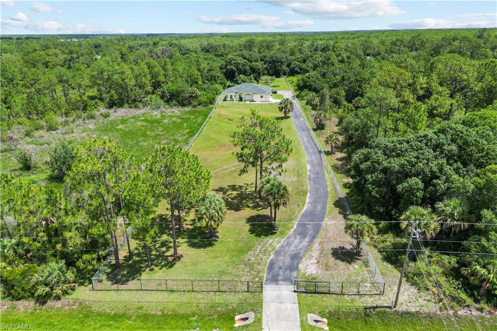 Expansive property featuring a paved driveway leading to a single-story residence
