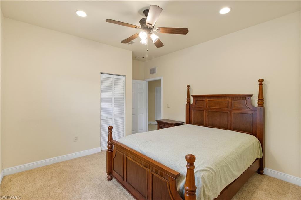 Carpeted bedroom featuring a louvered bifold closet door, recessed lighting, and a ceiling fan with integrated light fixture