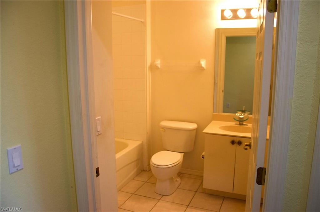 Bathroom featuring a white toilet, tile flooring, and a vanity with a circular basin sink and cabinet storage