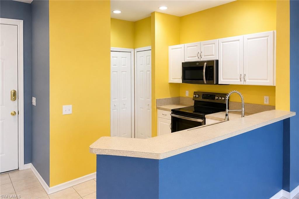 Kitchen featuring white cabinetry, black appliances including a built-in microwave and range, a double-basin sink with a gooseneck faucet, and light-colored countertops