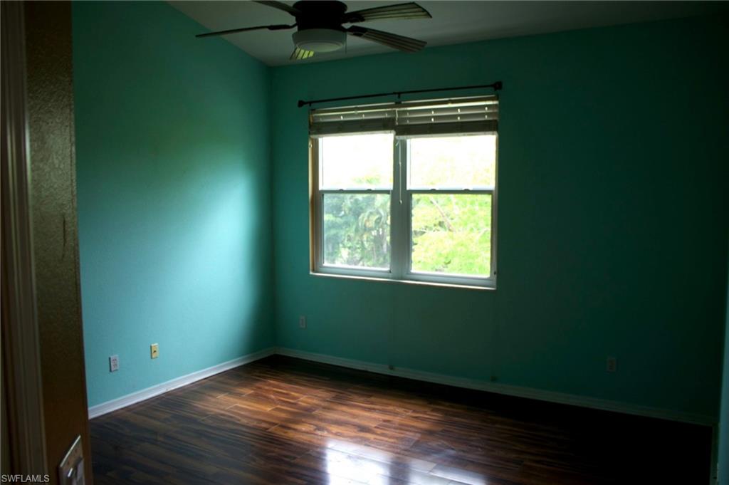 Spacious room featuring wood-finish flooring, a ceiling fan, and a large window with horizontal blinds