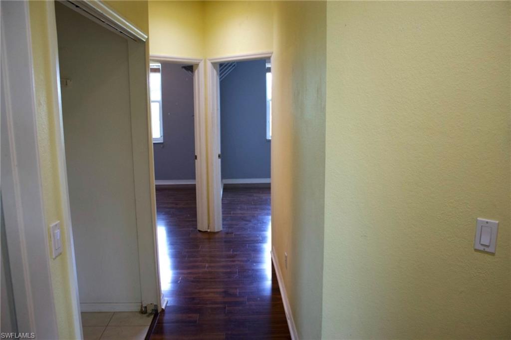 Hallway featuring textured walls, wood-finish flooring, and white trim