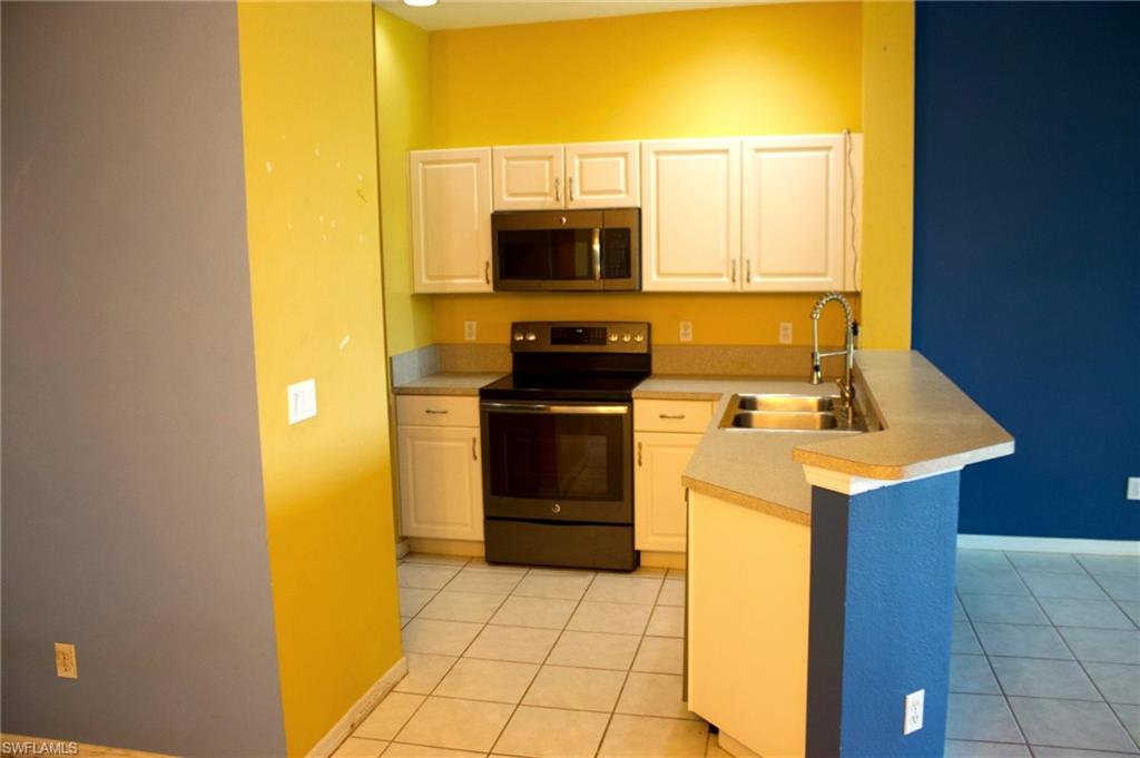 Kitchen featuring white cabinetry, black appliances, a double basin sink with a high-arc faucet, and tiled flooring