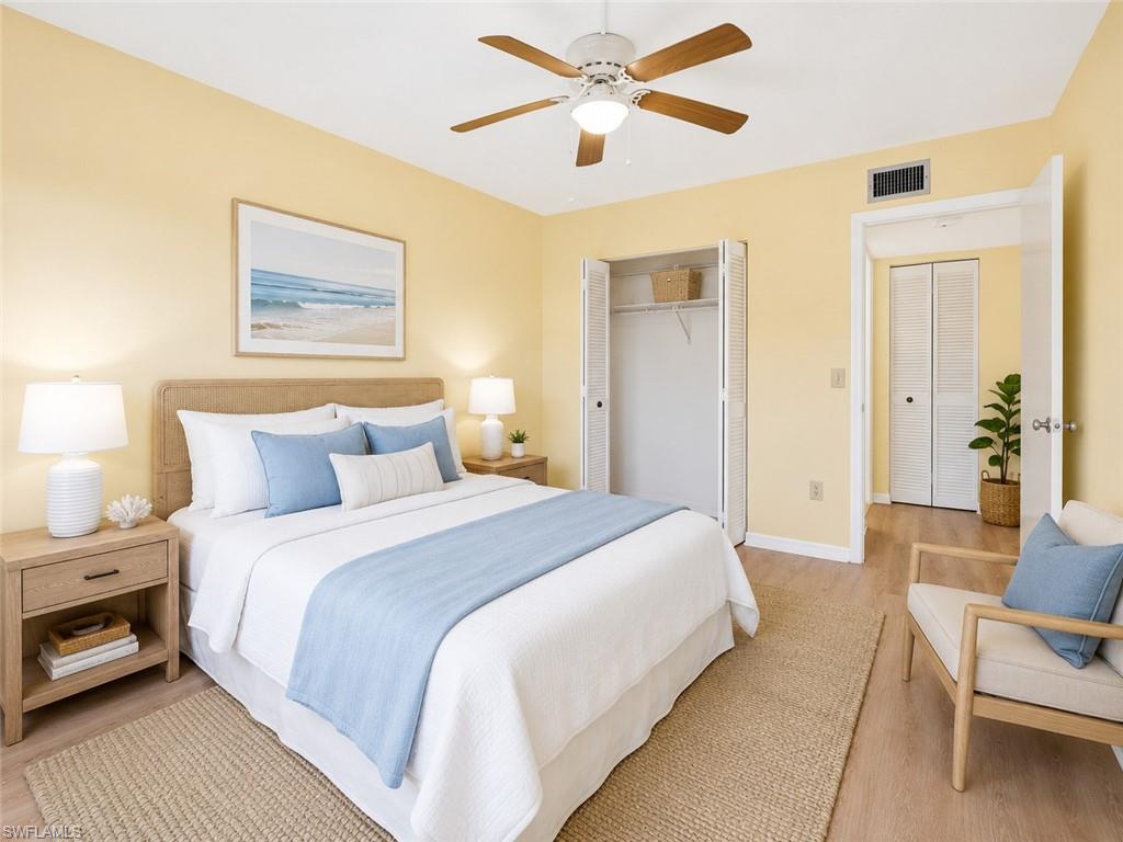 Spacious bedroom featuring light wood-finish flooring, a ceiling fan with integrated lighting, and a bi-fold closet