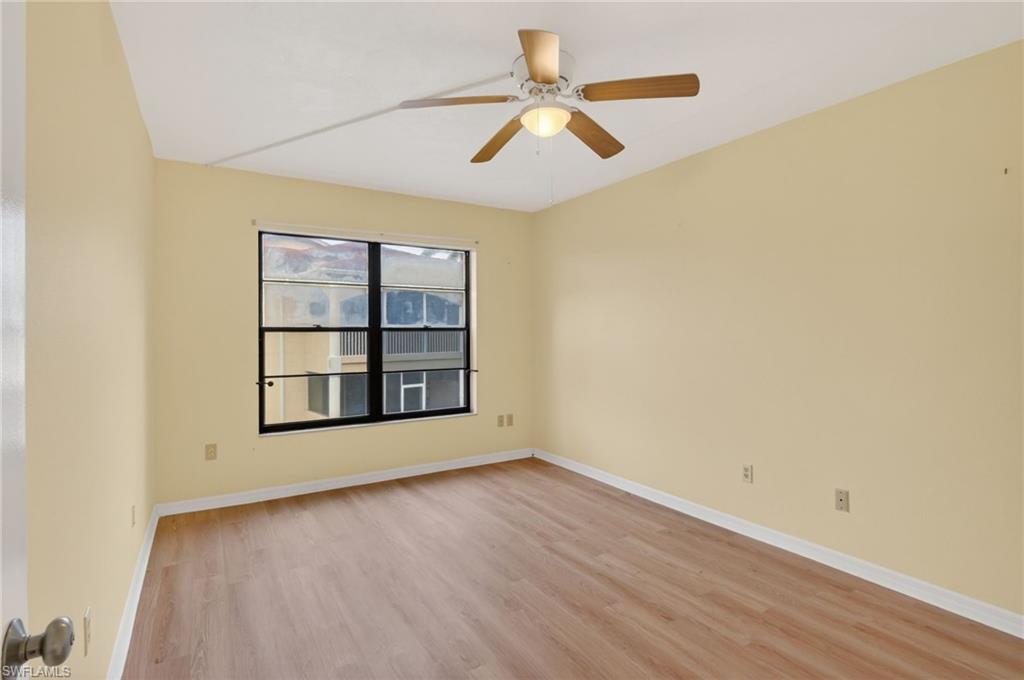 Interior space featuring wood-finish flooring, a ceiling fan with integrated lighting, and a large window with black framing