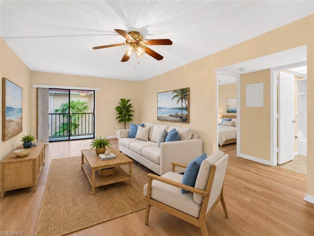 Living space featuring wood-finish flooring, a ceiling fan, and a glass sliding door opening to a private balcony with black railings
