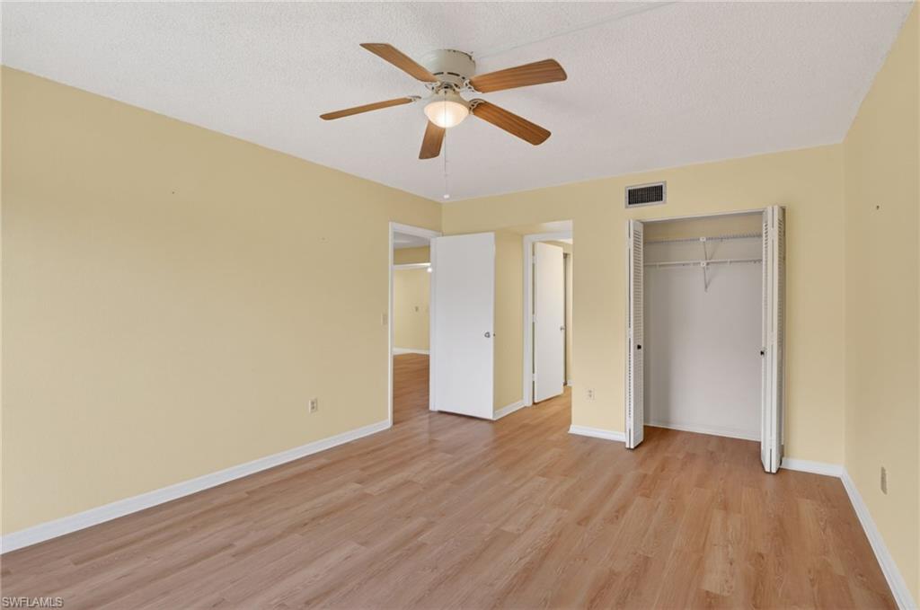 Spacious room featuring wood-finish flooring, light yellow walls, and white baseboards