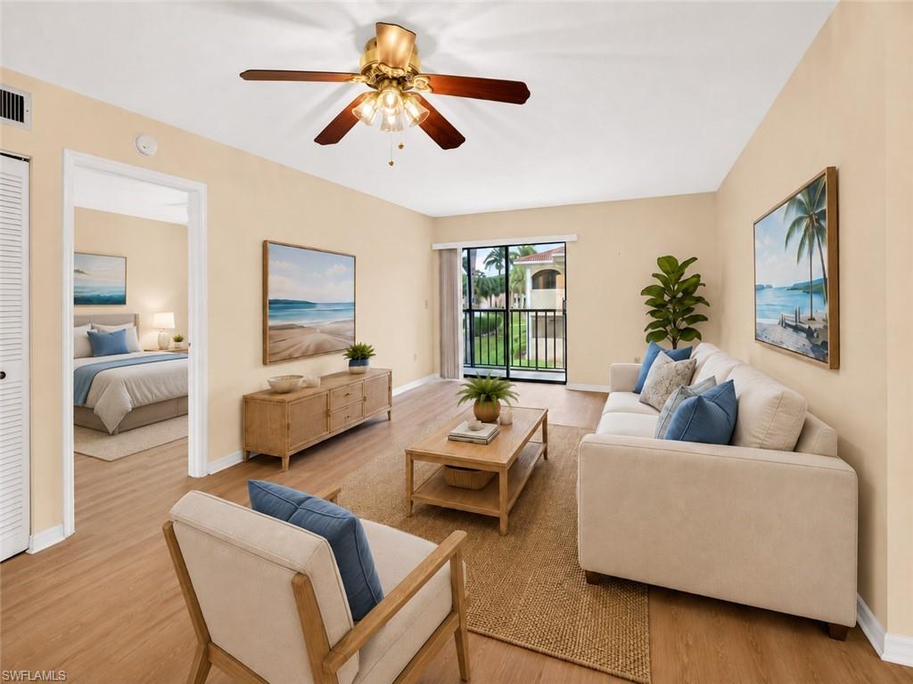 Living area featuring wood-finish flooring, a ceiling fan with light fixture, and a balcony with black metal railings