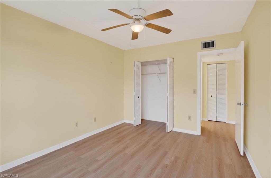 Room featuring wood-finish flooring, light yellow walls, and white baseboards