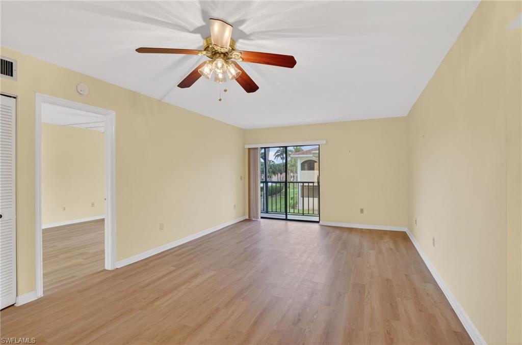 Spacious room featuring wood-finish flooring, a ceiling fan with integrated lighting, and a sliding glass door opening to a balcony