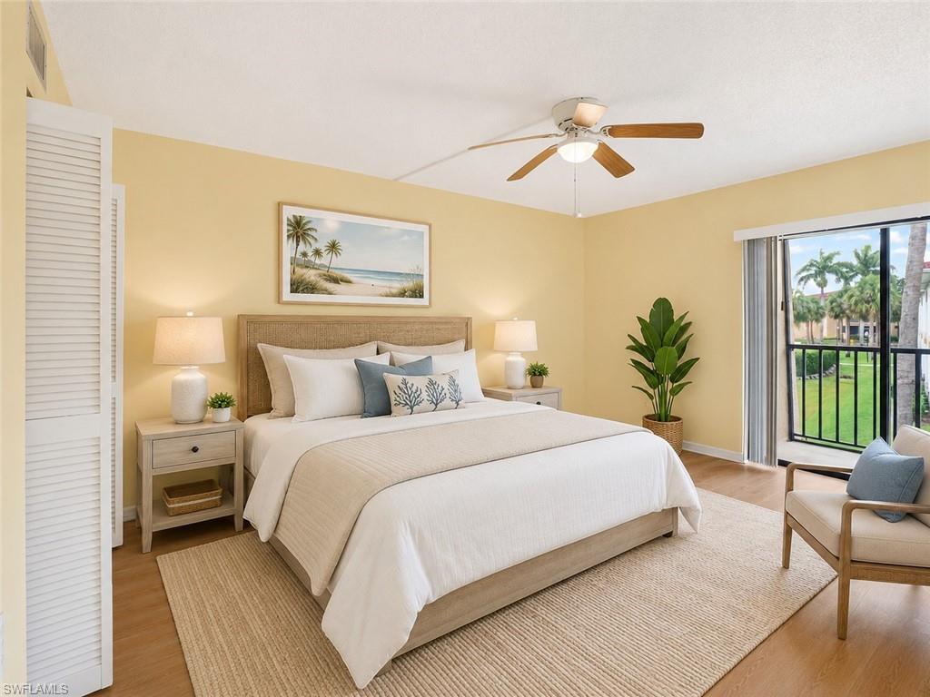 Spacious room with light wood-finish flooring, a ceiling fan with light fixture, louvered closet doors, and direct balcony access