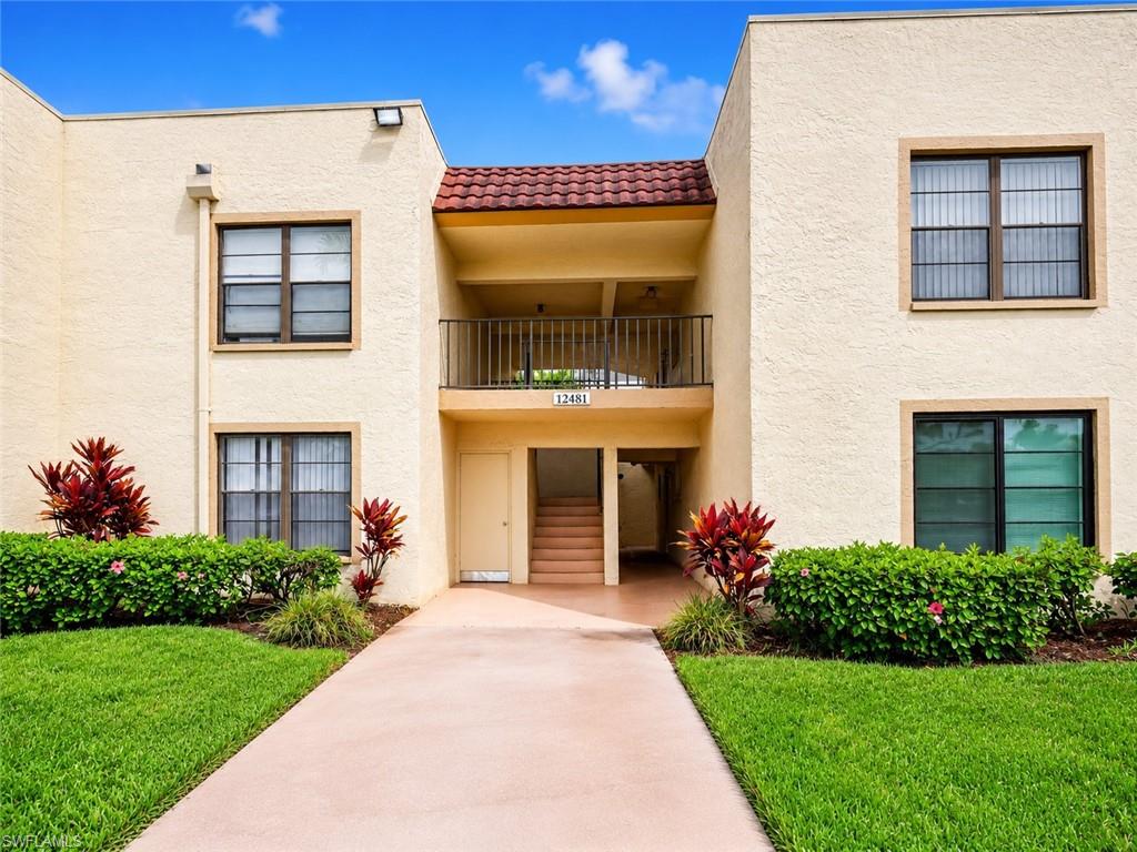Exterior facade featuring stucco finish, a red tile roof accent, and a second-story balcony with metal railings