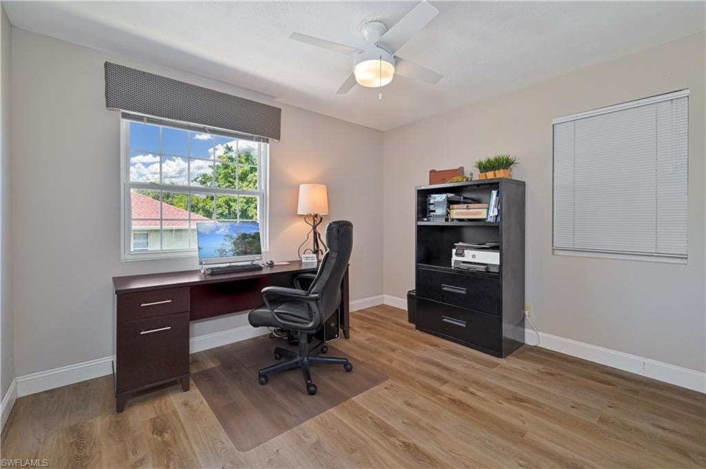 Wood-finish flooring, ceiling fan with integrated lighting, and multiple windows with blinds