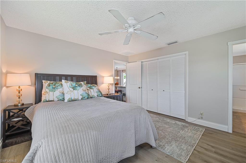 Wood-finish flooring, ceiling fan, white louvered closet doors, and recessed lighting