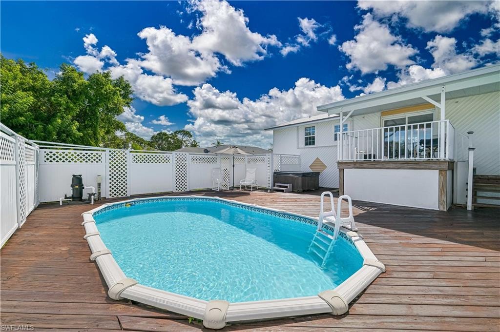 Expansive wood deck surrounding an above-ground pool, white lattice fencing, and a private balcony with white railings