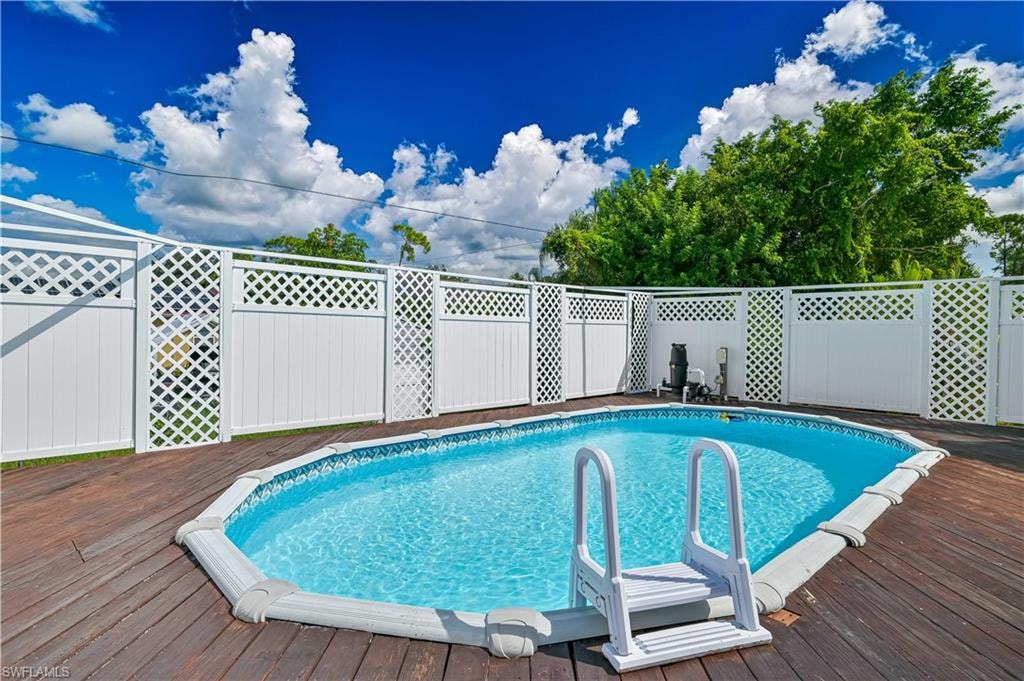 Above-ground pool with a white ladder, surrounded by a wood-finish deck