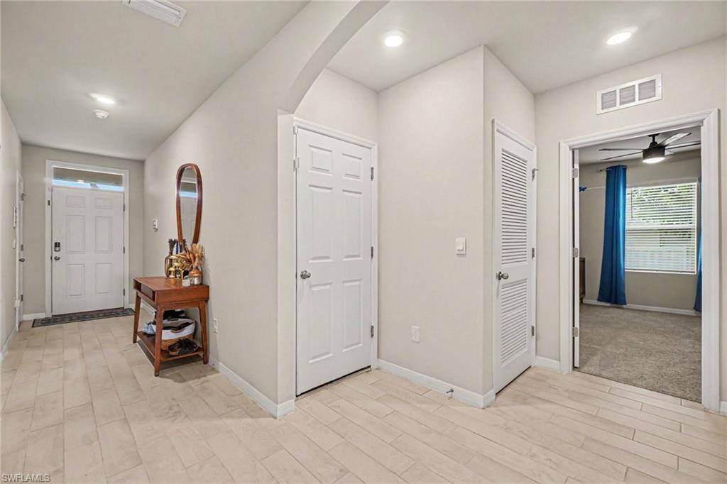 Entryway featuring light-toned plank flooring, recessed ceiling lighting, and a paneled front door with sidelight