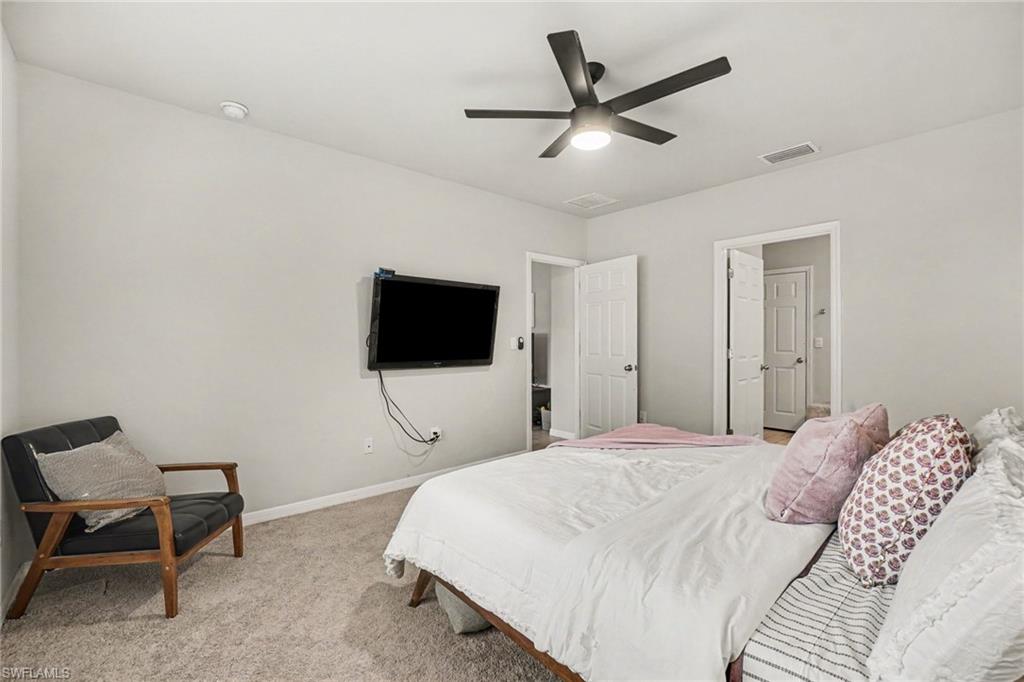 Carpeted room featuring light gray walls, a ceiling fan with integrated lighting, and white trim