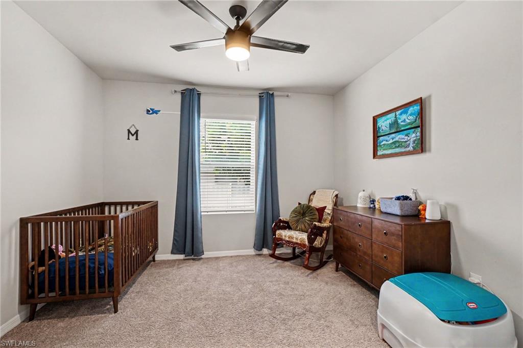 Spacious room featuring neutral carpeting, light-colored walls, and a ceiling fan with integrated lighting