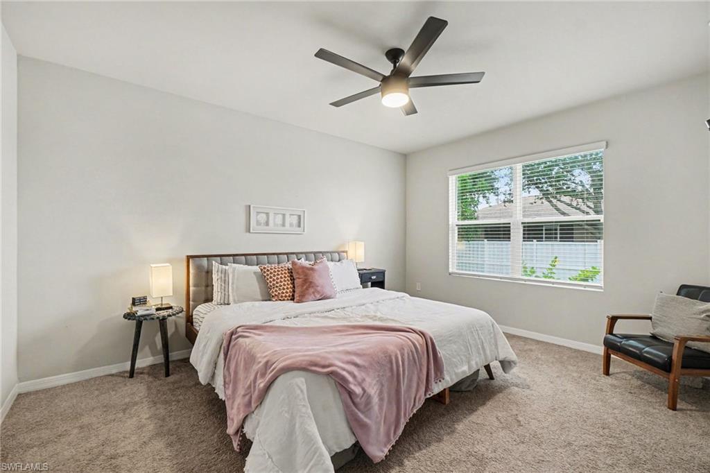 Carpeted bedroom featuring a ceiling fan, a large window with blinds, and light-toned walls