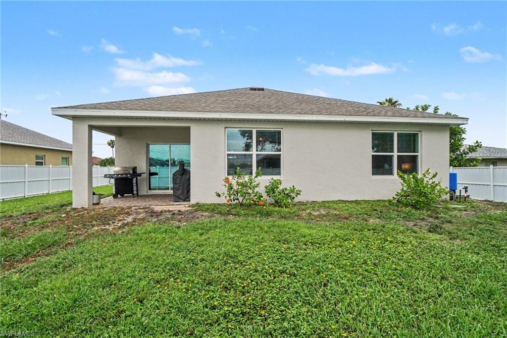 Rear exterior featuring a covered patio with concrete flooring, stucco siding, a shingle roof, and multiple windows