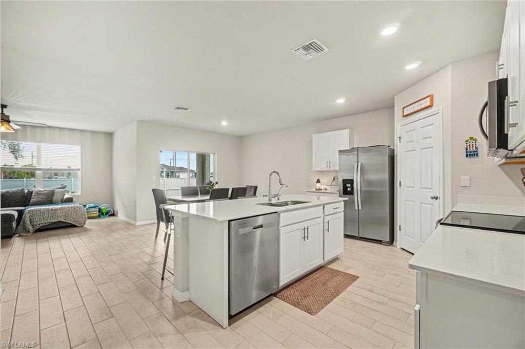 Open-concept kitchen featuring an island with a stainless steel sink and dishwasher