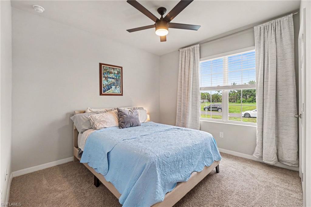 Bedroom featuring carpeted flooring, a ceiling fan with integrated lighting, and a large window with blinds and draperies