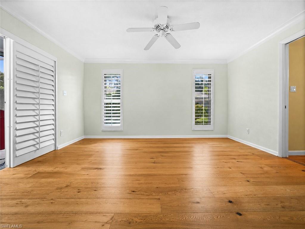 Spacious primary bedroom features warm wood flooring, abundant natural light, and direct access to the outdoor living area.