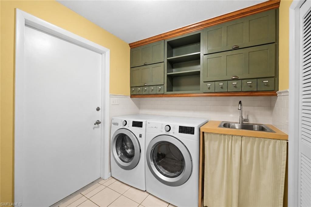 Convenient interior laundry room features side-by-side appliances, upper cabinetry, and additional storage space.