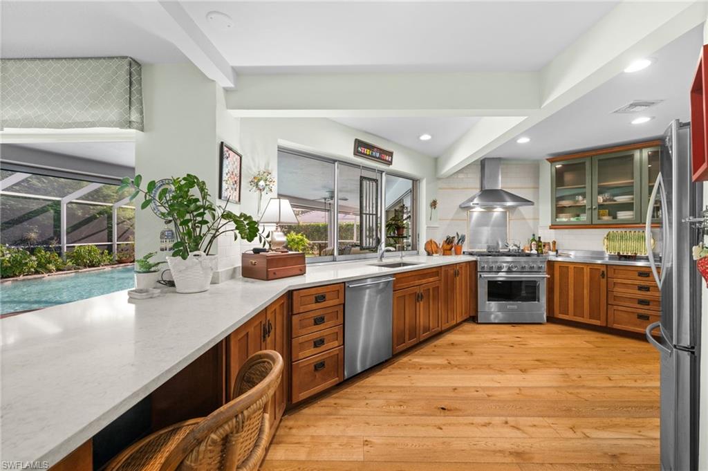 The updated kitchen is equipped with a gas stove, glass-fronted cabinets, and quartz countertops, and overlooks the outdoor retreat beyond.