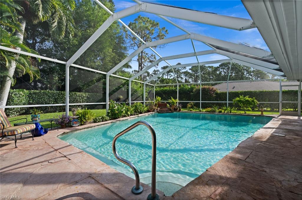Expansive screened pool and covered lanai offer a private outdoor retreat surrounded by tropical landscaping.