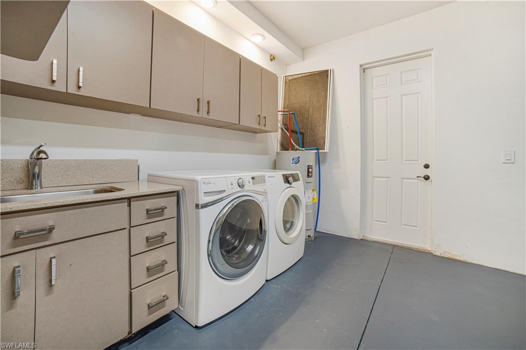 Laundry area featuring cabinets, sink, electric water heater, and washer and clothes dryer