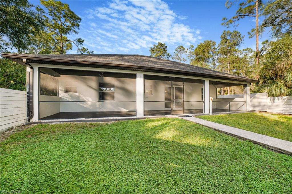 Rear view of house featuring a lawn and a sunroom