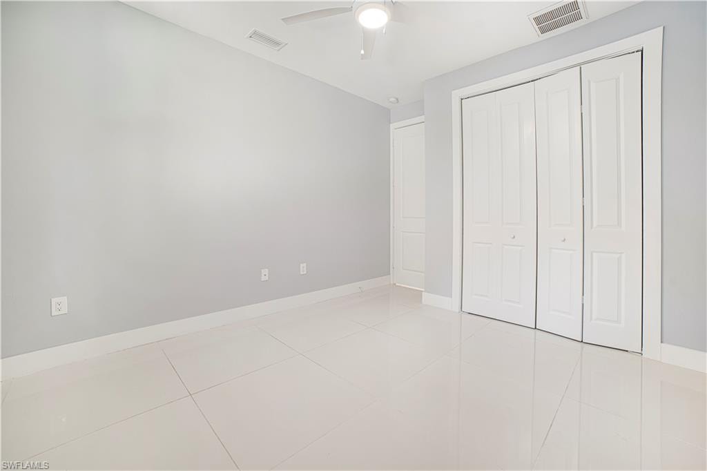 Unfurnished bedroom with a closet, light tile patterned floors, and ceiling fan