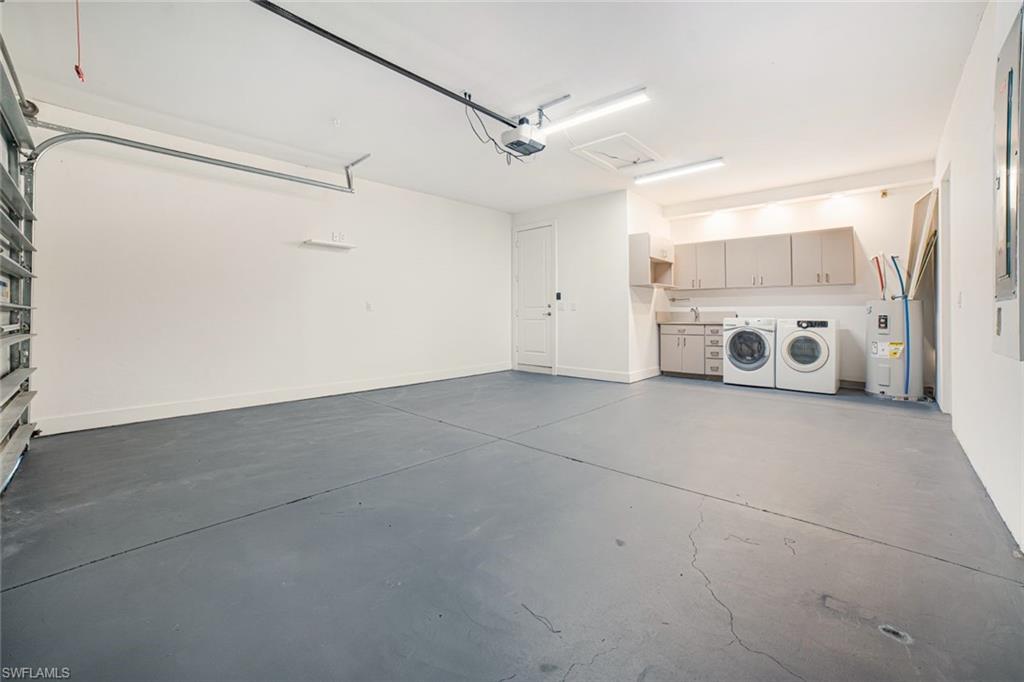 Garage featuring a garage door opener, water heater, and separate washer and dryer